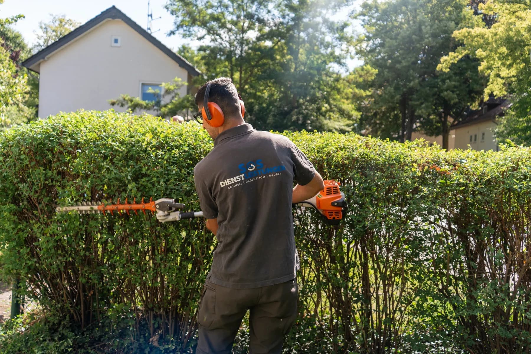 Mitarbeiter von SOS Dienstleistungen schneidet eine Hecke